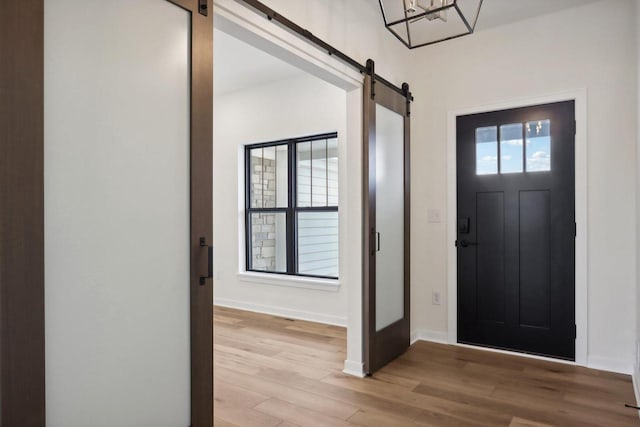 entryway with a barn door and light hardwood / wood-style floors