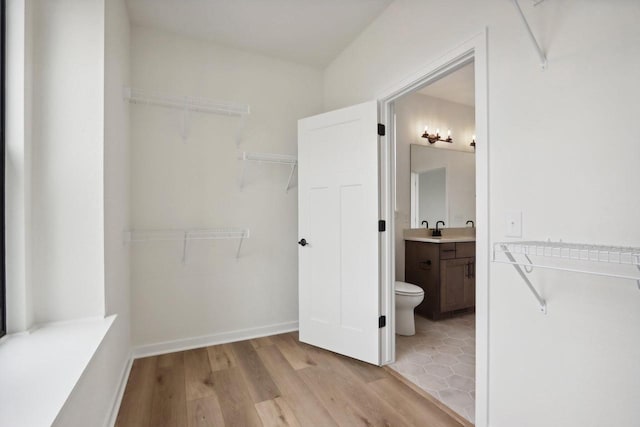 walk in closet with light wood-type flooring and sink