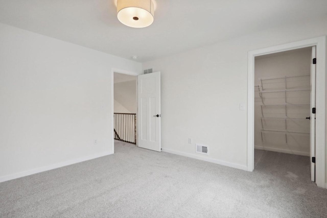 unfurnished bedroom with light colored carpet, a spacious closet, and a closet