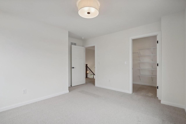 unfurnished bedroom featuring light colored carpet, a spacious closet, and a closet