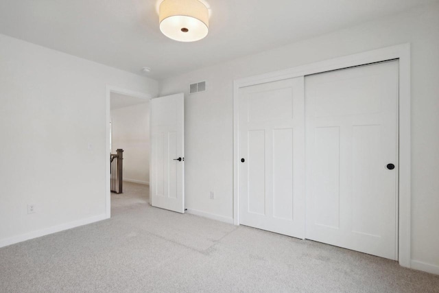 unfurnished bedroom with a closet and light colored carpet