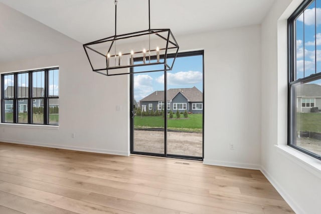 unfurnished dining area featuring a chandelier and light hardwood / wood-style floors