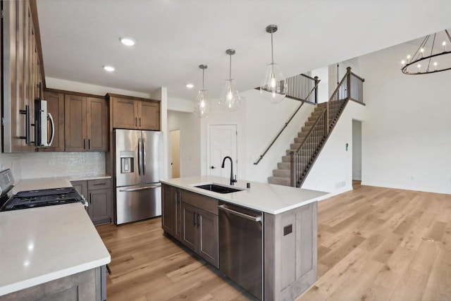 kitchen featuring pendant lighting, a kitchen island with sink, sink, light hardwood / wood-style flooring, and appliances with stainless steel finishes