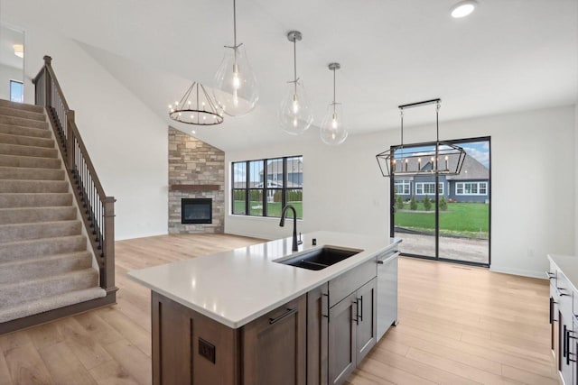 kitchen with pendant lighting, a healthy amount of sunlight, a stone fireplace, and sink