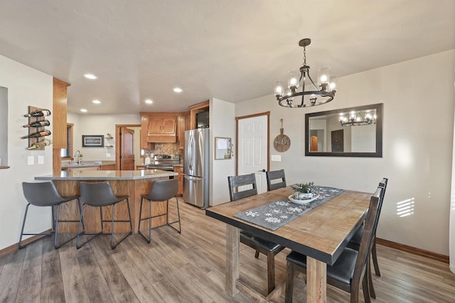 dining space featuring light hardwood / wood-style floors, a notable chandelier, and sink