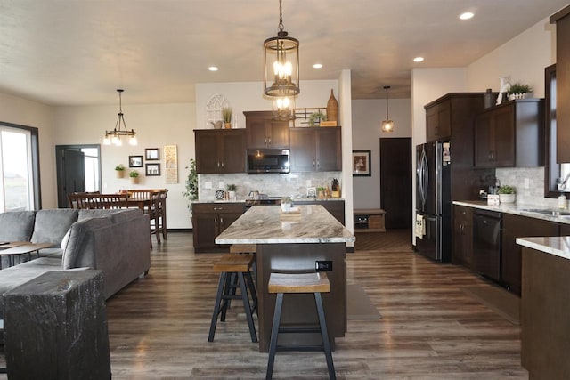 kitchen with appliances with stainless steel finishes, dark brown cabinets, sink, pendant lighting, and a kitchen island