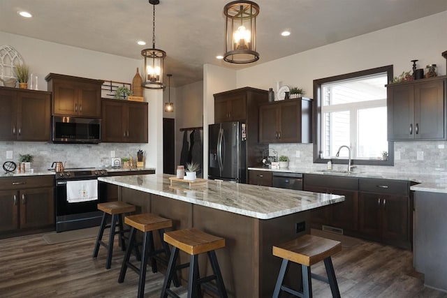 kitchen featuring a kitchen bar, appliances with stainless steel finishes, dark hardwood / wood-style flooring, sink, and a center island