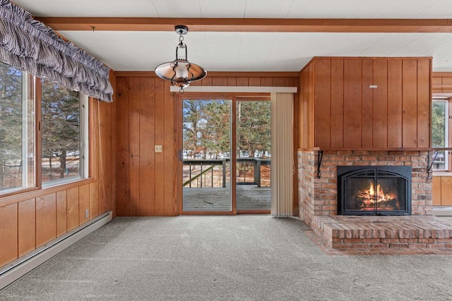 unfurnished living room featuring wooden walls, beam ceiling, a baseboard radiator, a fireplace, and carpet floors