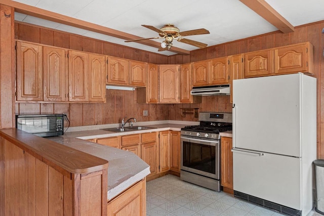 kitchen with kitchen peninsula, ceiling fan, sink, white refrigerator, and stainless steel range with gas cooktop