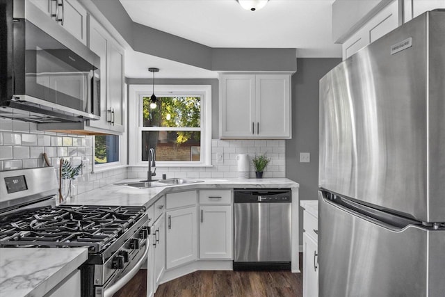 kitchen featuring white cabinets, appliances with stainless steel finishes, hanging light fixtures, and sink