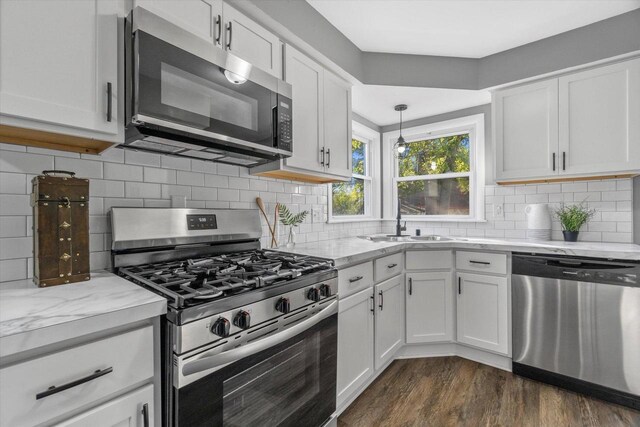 kitchen with appliances with stainless steel finishes, white cabinetry, hanging light fixtures, and sink