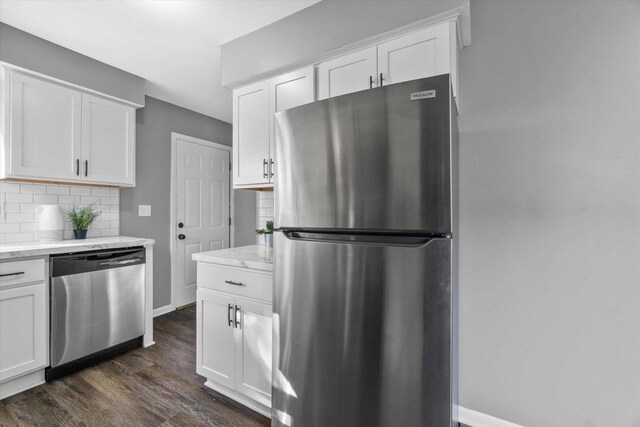 kitchen featuring light stone countertops, tasteful backsplash, stainless steel appliances, white cabinets, and dark hardwood / wood-style floors