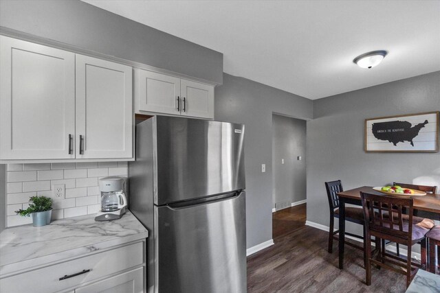 kitchen with stainless steel refrigerator, light stone countertops, dark hardwood / wood-style floors, backsplash, and white cabinets