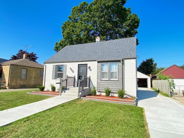 bungalow-style home with a front yard, a garage, and an outdoor structure