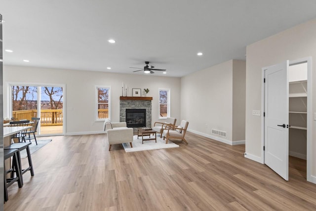 living room with a fireplace, light hardwood / wood-style flooring, and ceiling fan