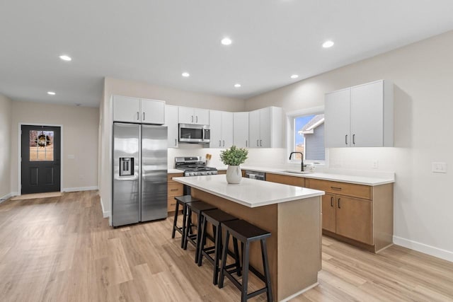 kitchen featuring appliances with stainless steel finishes, a breakfast bar, sink, a center island, and white cabinetry