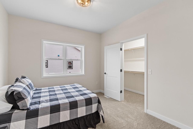 bedroom with light colored carpet, a spacious closet, and a closet