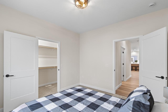 bedroom with light colored carpet, a spacious closet, and a closet