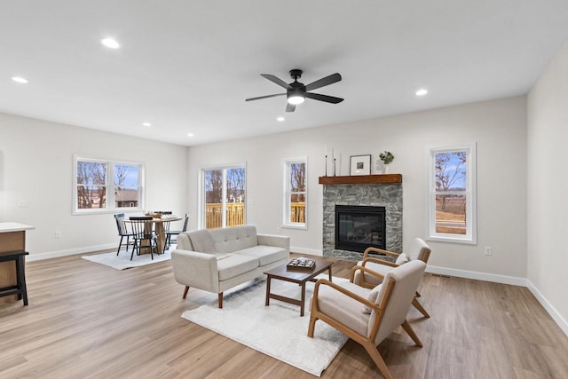 living room with ceiling fan, light wood-type flooring, and a fireplace