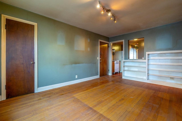 unfurnished living room featuring hardwood / wood-style floors and built in shelves