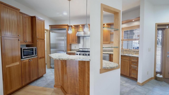 kitchen with pendant lighting, exhaust hood, sink, light stone countertops, and appliances with stainless steel finishes