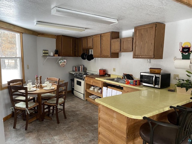 14239 S Eau Claire Acres, Gordon, WI 54838 - kitchen featuring a kitchen breakfast bar, kitchen peninsula, a textured ceiling, and white range with gas cooktop
