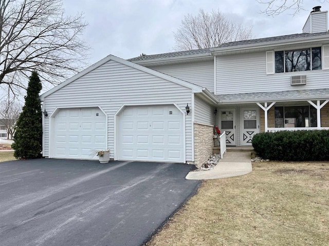 view of property featuring a garage and a wall unit AC