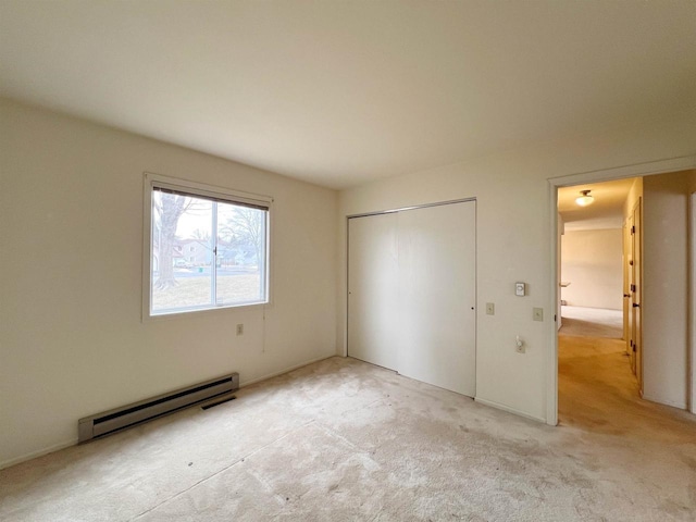 unfurnished bedroom with light colored carpet, baseboard heating, and a closet