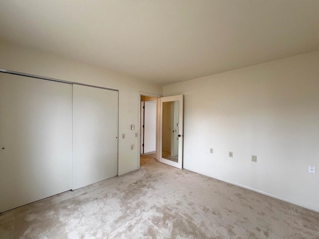 unfurnished bedroom with light carpet and a closet