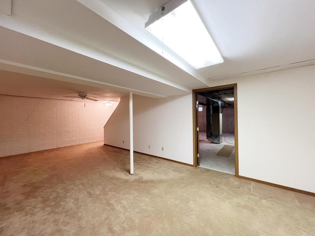 basement featuring ceiling fan, carpet floors, and brick wall