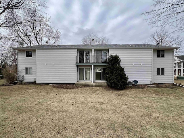 rear view of house with a lawn and a balcony