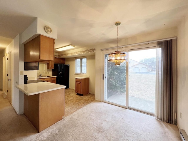 kitchen with stove, black fridge, sink, decorative light fixtures, and kitchen peninsula