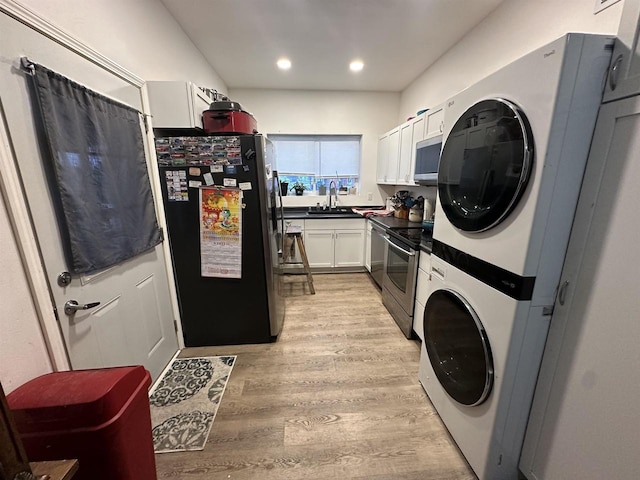 laundry area featuring light wood-type flooring, stacked washer / dryer, and sink