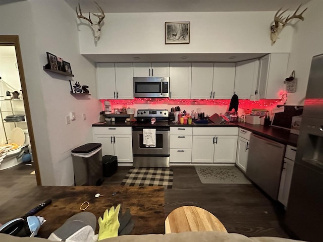 kitchen with white cabinets, appliances with stainless steel finishes, and dark hardwood / wood-style floors