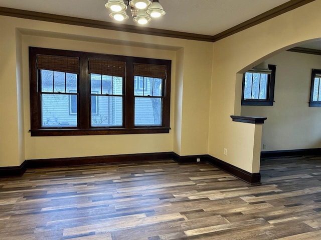 empty room featuring a notable chandelier, dark hardwood / wood-style flooring, and crown molding