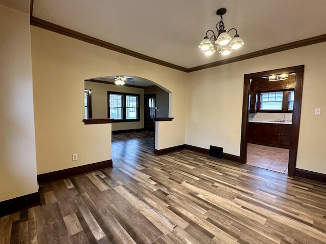 unfurnished dining area with hardwood / wood-style flooring, ceiling fan with notable chandelier, sink, and crown molding