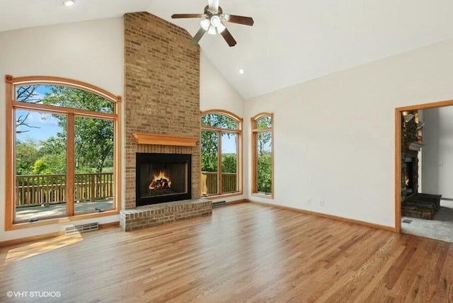 unfurnished living room featuring a brick fireplace, hardwood / wood-style floors, high vaulted ceiling, and ceiling fan