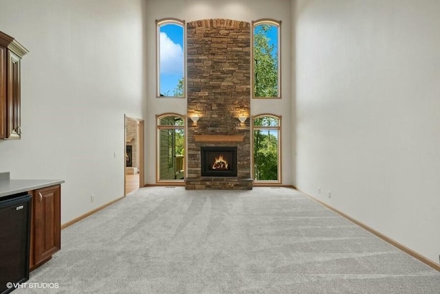 unfurnished living room with a towering ceiling, light carpet, and a fireplace