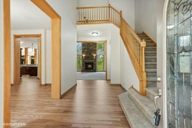 foyer featuring hardwood / wood-style flooring, a large fireplace, and a towering ceiling