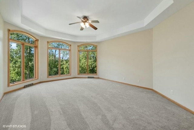 unfurnished room with carpet, ceiling fan, and a tray ceiling