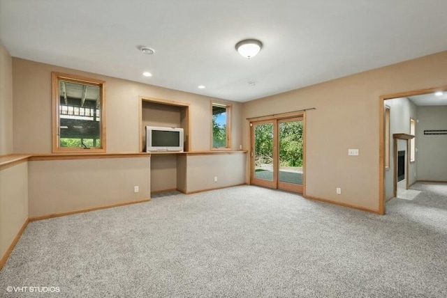 unfurnished living room featuring light carpet and built in desk