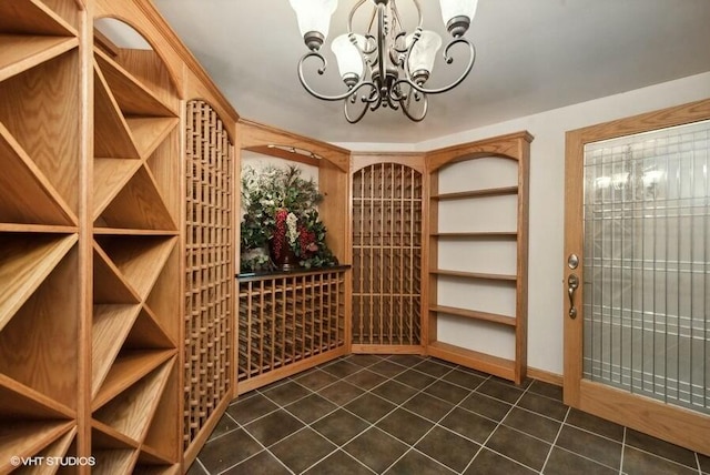 wine area with dark tile patterned floors and a chandelier