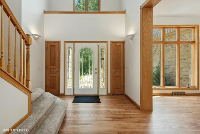 foyer entrance featuring a towering ceiling and light hardwood / wood-style floors