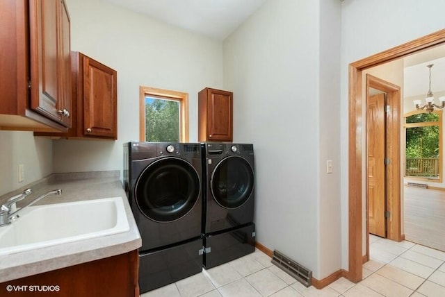 laundry room featuring a notable chandelier, light tile patterned floors, cabinets, and washing machine and clothes dryer