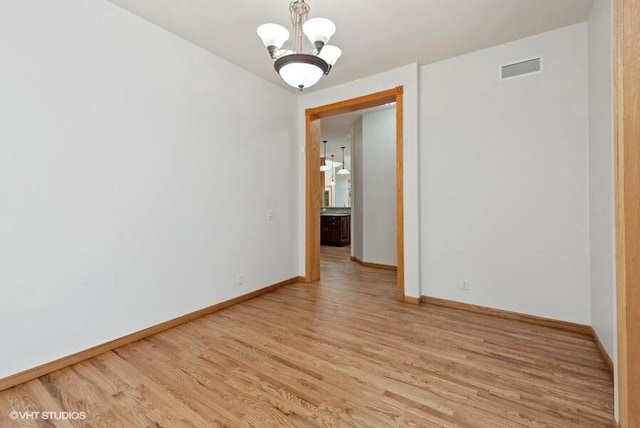 spare room with a chandelier and light hardwood / wood-style floors