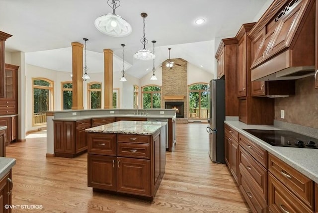 kitchen with light hardwood / wood-style flooring, a kitchen island, pendant lighting, stainless steel appliances, and a fireplace