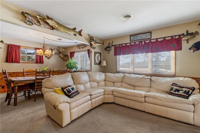 living room featuring carpet, a notable chandelier, a textured ceiling, and a wealth of natural light