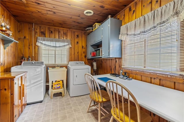 laundry area with cabinets, wood ceiling, washer and clothes dryer, sink, and wood walls