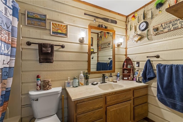 bathroom featuring wood walls, vanity, and toilet