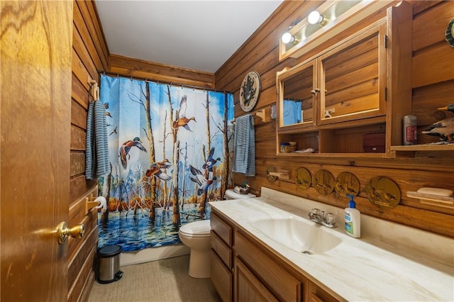 bathroom featuring vanity, toilet, and wooden walls